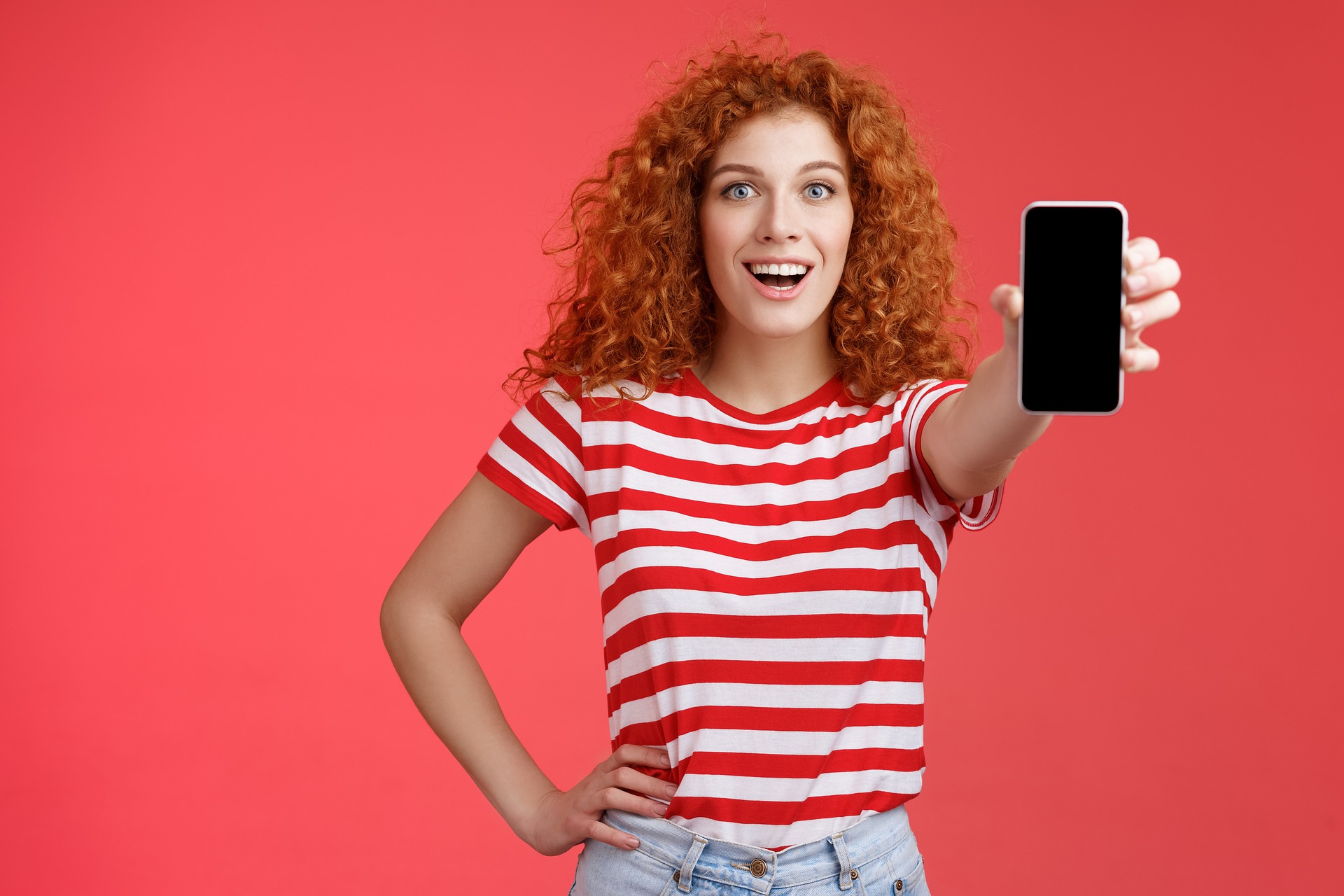 Femme rousse portant un t-shirt rayé et tenant un téléphone portable