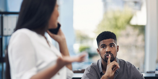 Un homme au travail demandant à une femme de faire moins de bruits en téléphonant