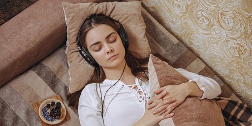 Une jeune femme en train d'écouter des podcasts le soir